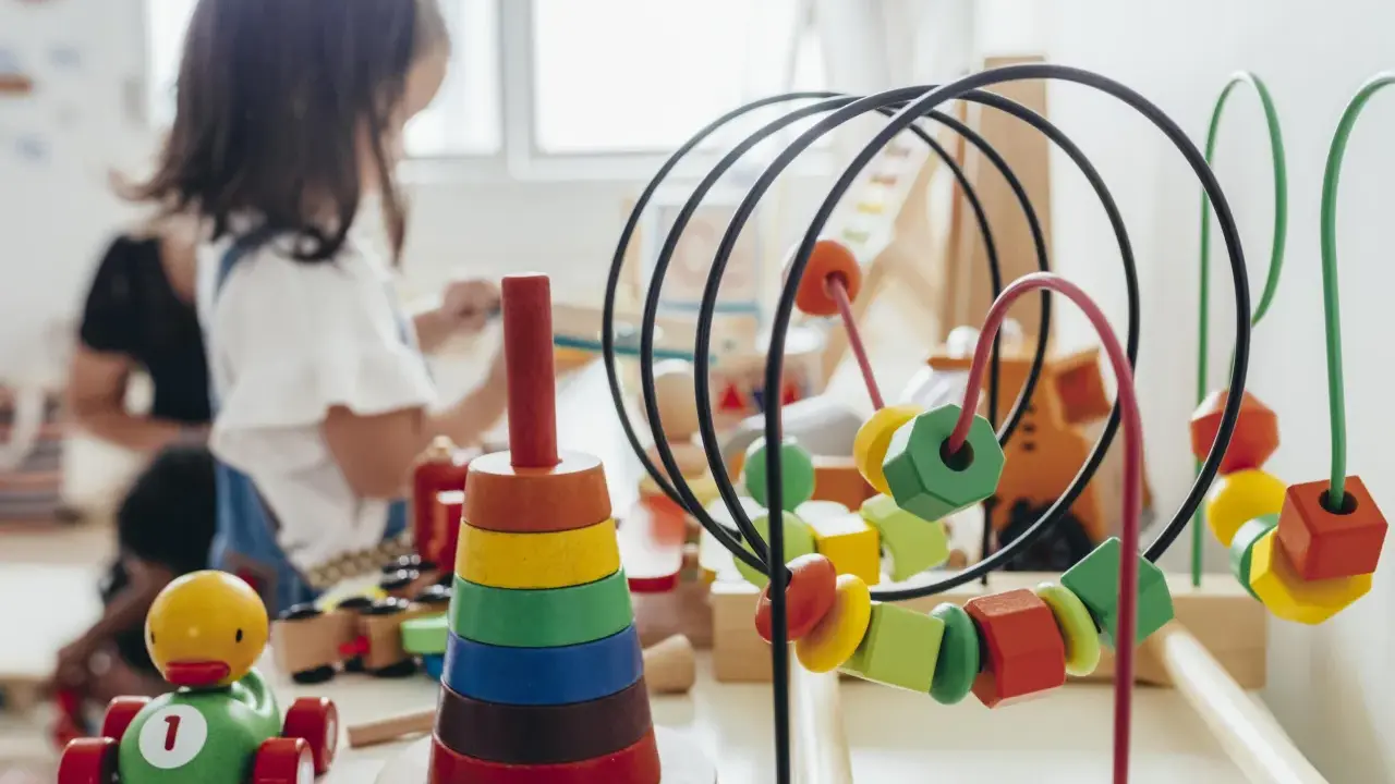 Juguetes de madera coloridos, como un cochecito de pato y un ábaco, forman parte de una guía Montessori para el aprendizaje infantil.