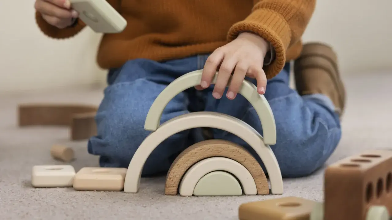 Niño jugando con bloques de madera, creando un arcoíris. Un ejemplo de método Montessori en casa para el desarrollo infantil.