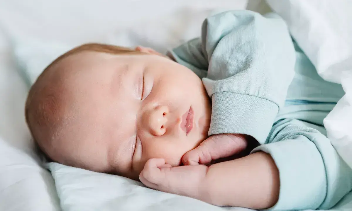 Bebé durmiendo plácidamente, con su mano cerca de la cara, en un ciclo sueño bebé perfecto.
