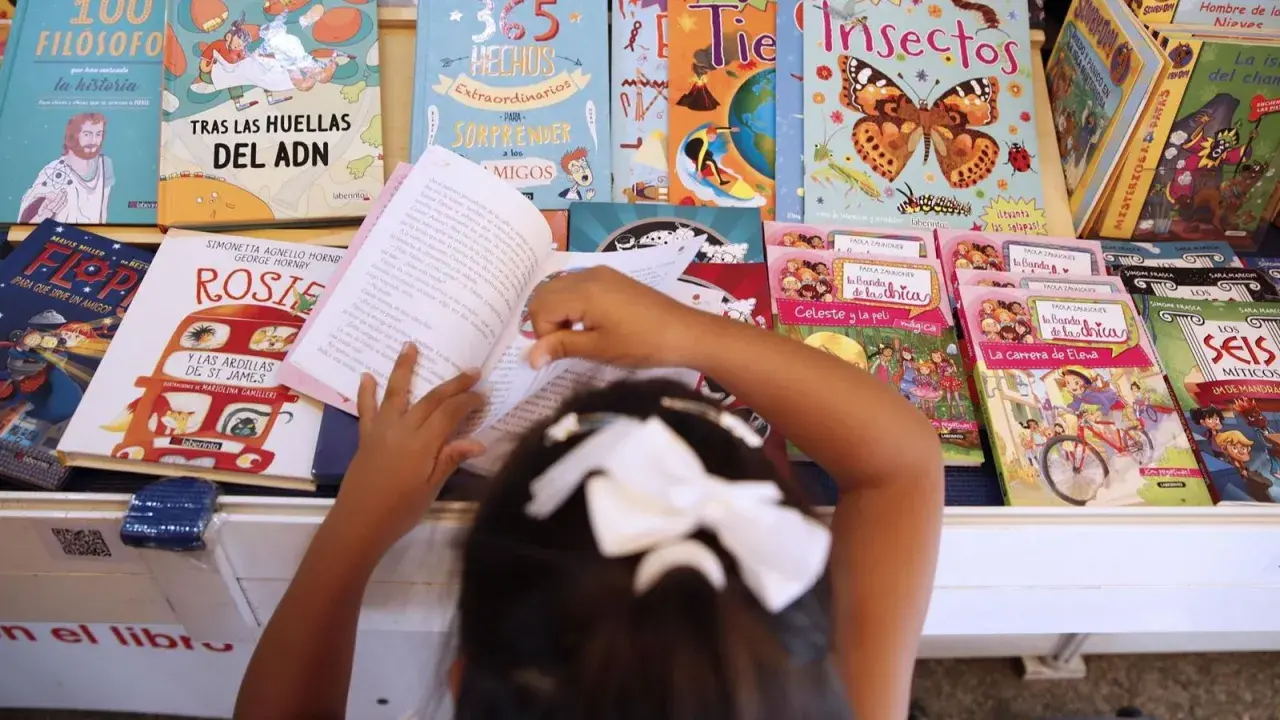 Niña lee libros sobre cuentos de igualdad de género, rodeada de coloridas portadas que inspiran a la imaginación.