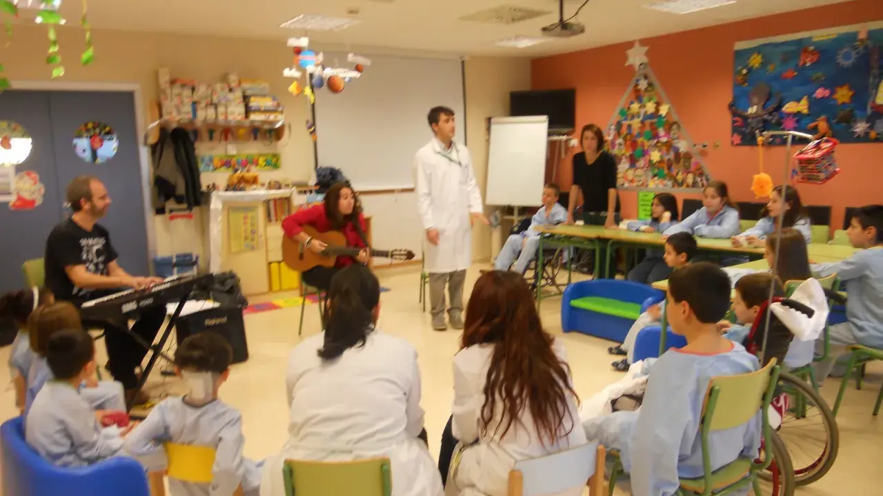 Niños y adultos participan en estaciones de aprendizaje, con música y actividades creativas.