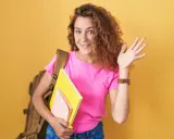 Chica sonriente con mochila y libros, lista para el colegio. ¡Bienvenida!