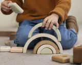Niño jugando con bloques de madera, creando un arcoíris. Un ejemplo de método Montessori en casa para el desarrollo infantil.