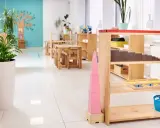 Un aula Montessori 0-3 años con mesas bajas, estanterías de madera y materiales didácticos como la torre rosa.