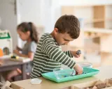 Niño concentrado en actividad de trasvase en un aula Montessori España.