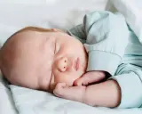 Bebé durmiendo plácidamente, con su mano cerca de la cara, en un ciclo sueño bebé perfecto.