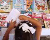 Niña lee libros sobre cuentos de igualdad de género, rodeada de coloridas portadas que inspiran a la imaginación.
