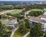 Vista aérea de un colegio Montessori con campos deportivos, piscina y edificios modernos rodeados de árboles.