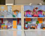 Casa de muñecas con habitaciones detalladas, mostrando actividades de la vida diaria ejemplos como baño, cocina y sala.