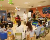 Niños y adultos participan en estaciones de aprendizaje, con música y actividades creativas.