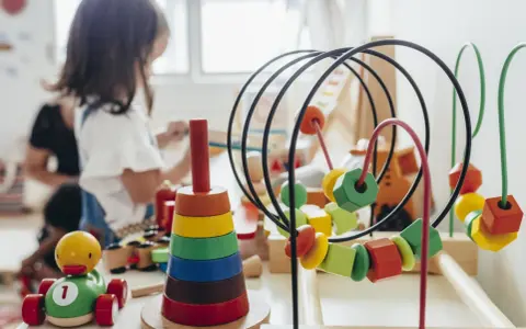 Juguetes de madera coloridos, como un cochecito de pato y un ábaco, forman parte de una guía Montessori para el aprendizaje infantil.