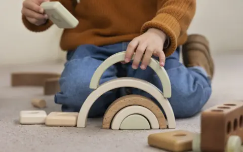 Niño jugando con bloques de madera, creando un arcoíris. Un ejemplo de método Montessori en casa para el desarrollo infantil.