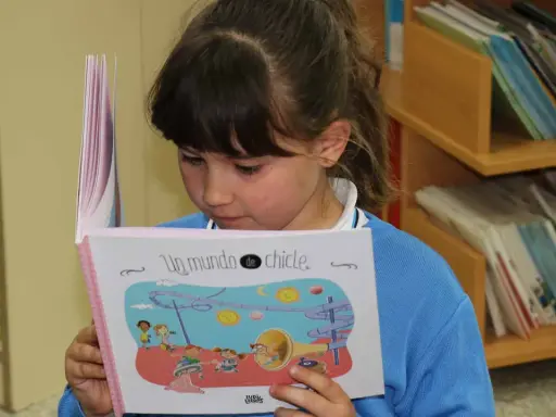 Niña leyendo un libro ilustrado, parte de una colección de libros por edades.