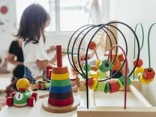 Juguetes de madera coloridos, como un cochecito de pato y un ábaco, forman parte de una guía Montessori para el aprendizaje infantil.