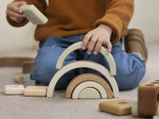 Niño jugando con bloques de madera, creando un arcoíris. Un ejemplo de método Montessori en casa para el desarrollo infantil.