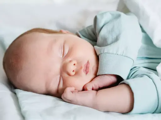 Bebé durmiendo plácidamente, con su mano cerca de la cara, en un ciclo sueño bebé perfecto.