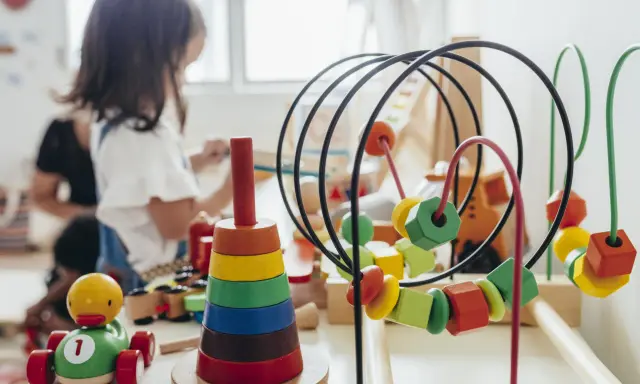 Juguetes de madera coloridos, como un cochecito de pato y un ábaco, forman parte de una guía Montessori para el aprendizaje infantil.