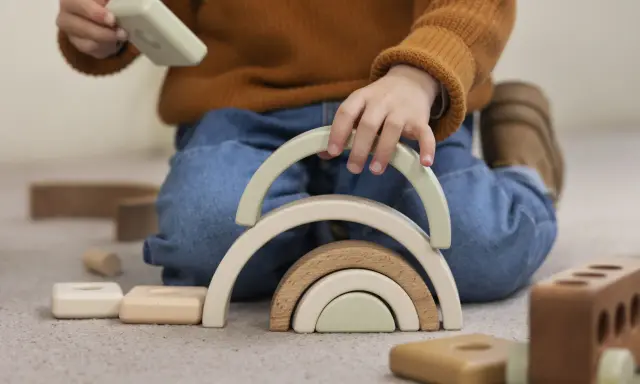 Niño jugando con bloques de madera, creando un arcoíris. Un ejemplo de método Montessori en casa para el desarrollo infantil.