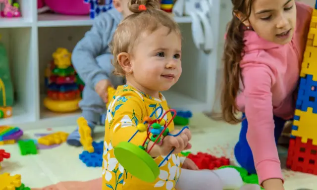 Niños jugando con bloques y juguetes, fomentando el desarrollo del niño de 0 a 6 años.