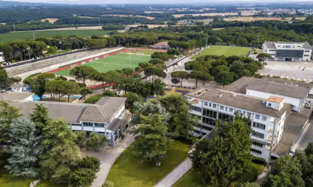 Vista aérea de un colegio Montessori con campos deportivos, piscina y edificios modernos rodeados de árboles.
