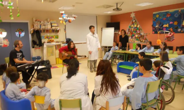 Niños y adultos participan en estaciones de aprendizaje, con música y actividades creativas.