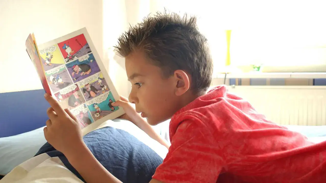 Ni&ntilde;o concentrado leyendo un comic infantil de Pato Donald y sus amigos.