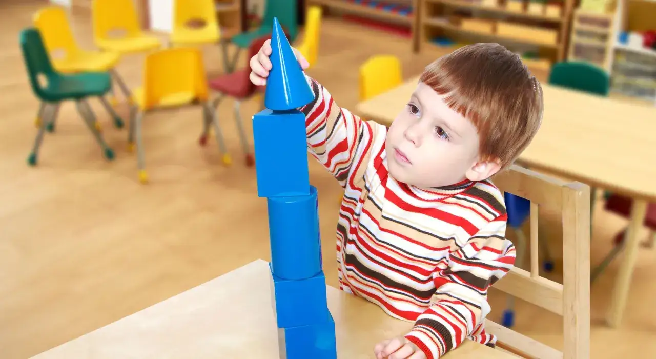 Ni&ntilde;o concentrado apilando bloques azules. &iexcl;Ayudame a hacerlo por mi mismo!