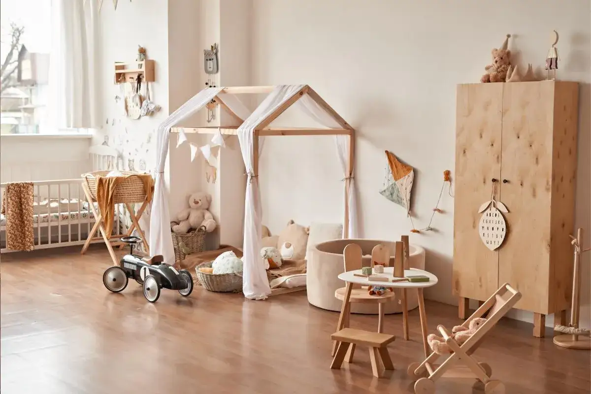 Habitación infantil con cuna, tienda de campaña de madera, peluches y juguetes. Un espacio ideal para el método Montessori en casa, fomentando el juego y el aprendizaje.