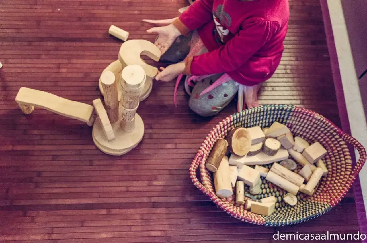 Niña jugando con bloques de madera, fomentando la creatividad y el aprendizaje a través de la pedagogía Waldorf.