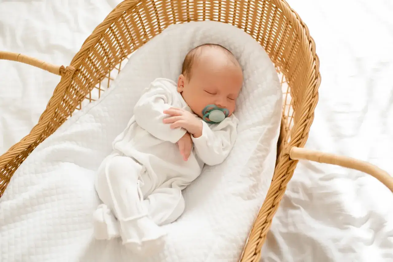 Beb&eacute; de 2 meses durmiendo pl&aacute;cidamente en su mois&eacute;s de mimbre, con chupete. Una imagen que evoca la paz de la rutina de sue&ntilde;o bebe 2 meses.