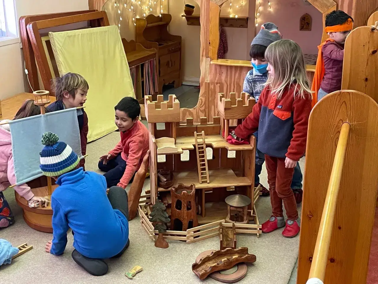 Ni&ntilde;os juegan con castillo de madera, fomentando el aprendizaje Waldorf Montessori.