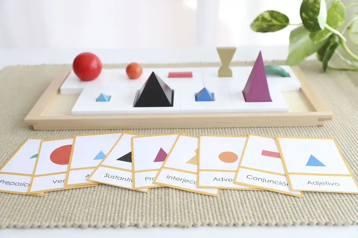 Juego de mesa con figuras geom&eacute;tricas y tarjetas que representan simbolos gramaticales montessori.