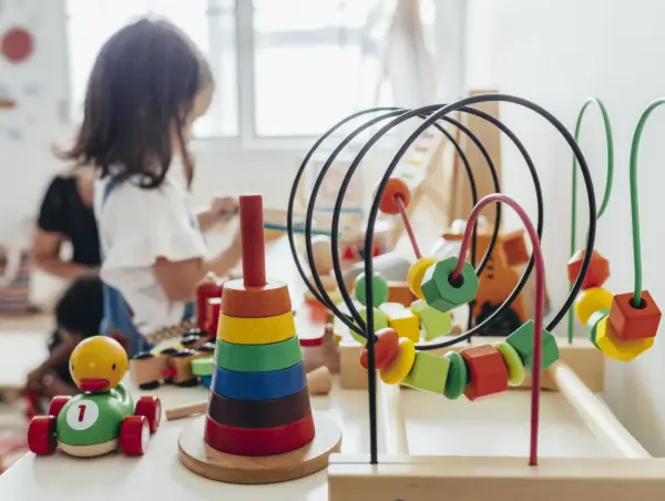 Juguetes de madera coloridos, como un cochecito de pato y un ábaco, forman parte de una guía Montessori para el aprendizaje infantil.